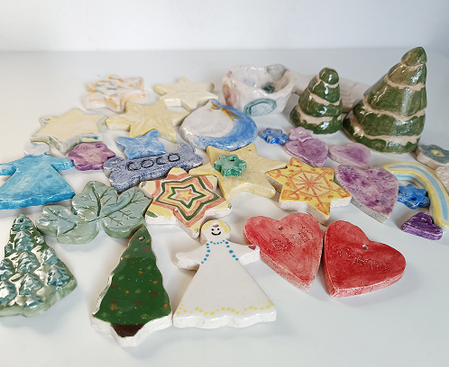 Colección de adornos de cerámica hechos a mano que incluyen estrellas, corazones, árboles de Navidad y figuras de ángeles de diversos colores.
