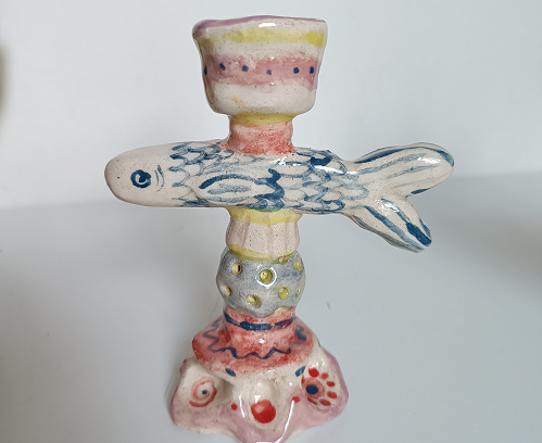 Portavelas de cerámica artesanal con diseño de pez azul y detalles decorativos en relieve con colores pastel.