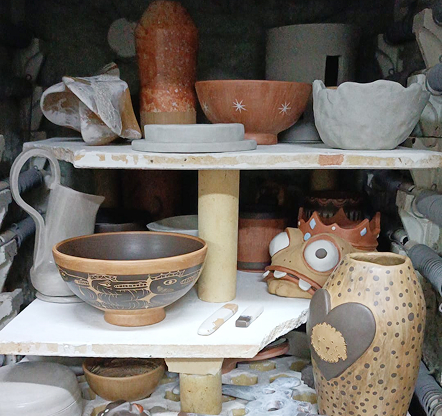 Estantería con piezas de cerámica decoradas, cuencos y figuras artesanales de la tienda Cerámica y Más