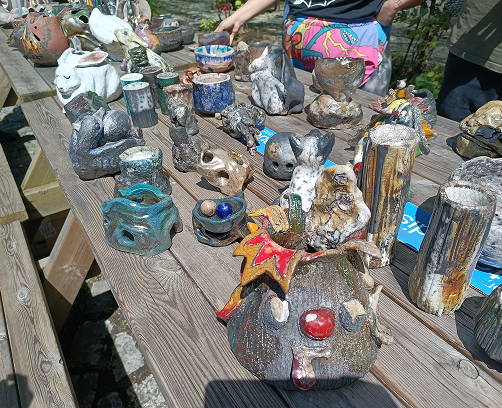 Varios cuencos de cerámica Raku enfriándose al aire libre, mostrando las características grietas negras del craquelado sobre esmalte blanco.