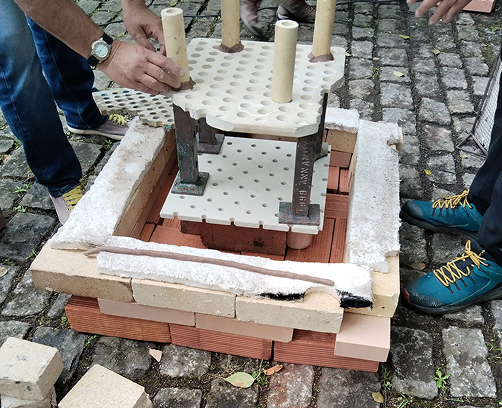 Limpieza de las piezas de Raku con agua y estropajo para eliminar los restos de ceniza y revelar los colores metálicos y el craquelado final.