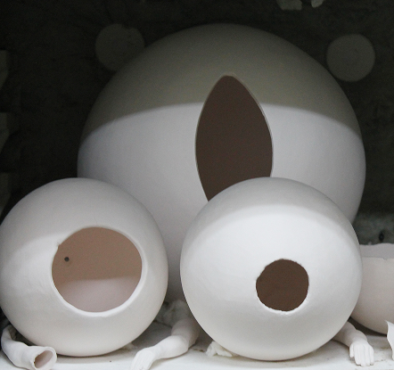 Esculturas esféricas de cerámica blanca con aperturas geométricas en el taller de Cerámica y Más.