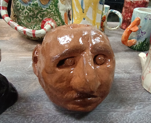 Bustos de cerámica vidriada en tonos terracota, mostrando una técnica de modelado manual detallada con expresiones faciales marcadas.
