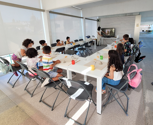 Grupo de niños participando en un taller de cerámica temática, trabajando con arcilla en una mesa compartida en Cerámica y Más.