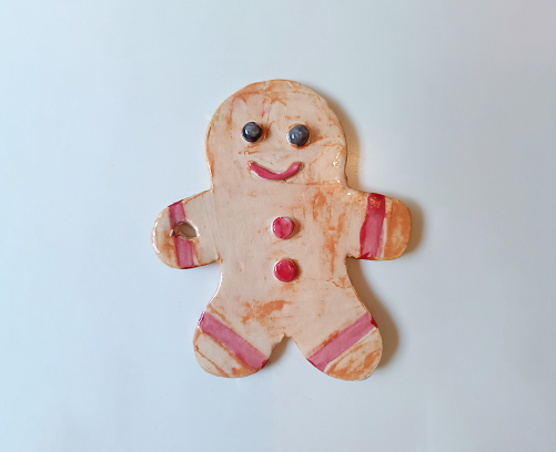 Adorno de cerámica de hombre de jengibre en color canela con una sonrisa pintada, mejillas rosadas y detalles en relieve.