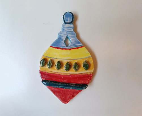 Figura de cerámica de un regalo navideño con textura de estrellas amarillas, lazo rojo y base dividida en azul y blanco