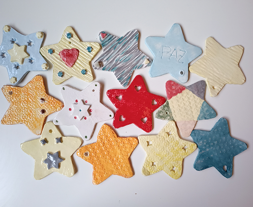 Figura de cerámica de un regalo navideño con textura de estrellas amarillas, lazo rojo y base dividida en azul y blanco